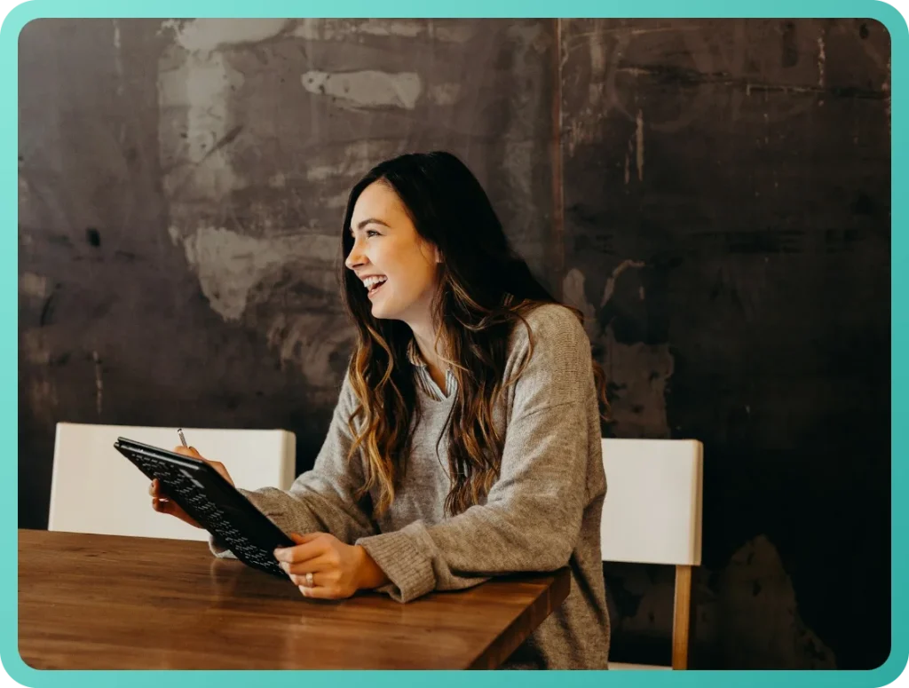 Business owner smiling while reviewing payroll on a tablet at a restaurant table