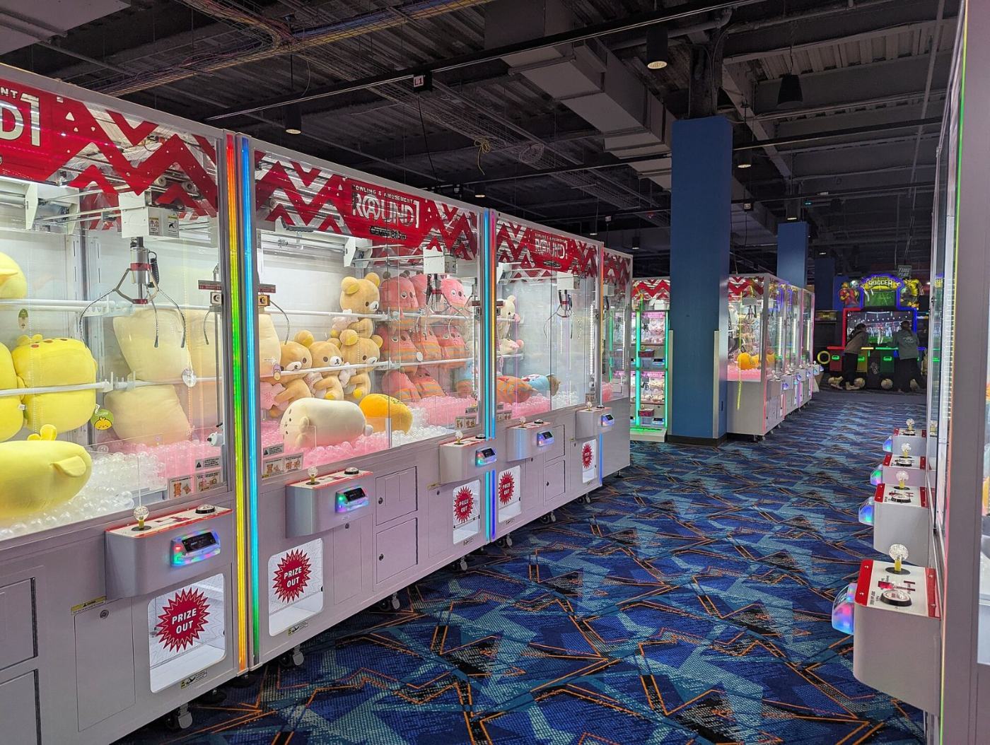 Row of prize crane machines filled with plush toys in an arcade